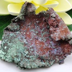May include: A piece of raw copper with a green patina. The copper has a rough, textured surface and is irregularly shaped.