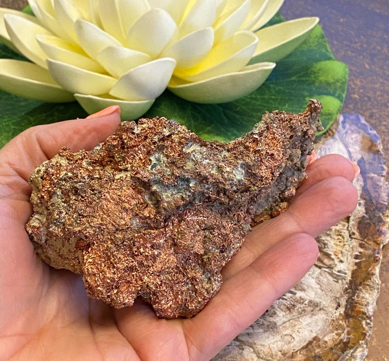 Puede incluir: Una roca grande, rugosa, de color cobre con un brillo met&aacute;lico. La roca tiene una forma irregular y dentada y est&aacute; cubierta de peque&ntilde;as formaciones cristalinas.