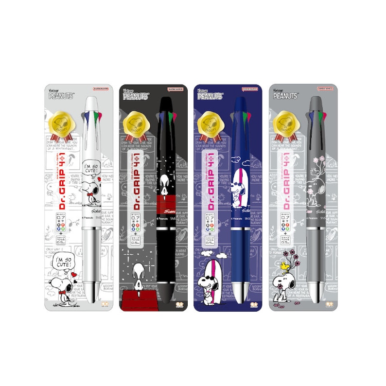 May include: Four different colored Dr. Grip 4+1 mechanical pencils with Peanuts characters. The pencils are silver, black, blue, and gray. Each pencil has a different Peanuts character on it. The text "Dr. Grip 4+1" is printed on each pencil.