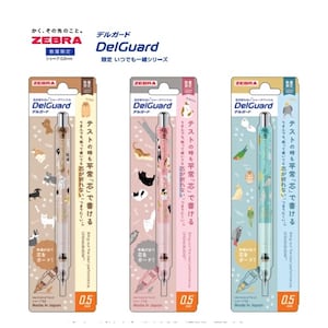 Puede incluir: Tres portaminas Zebra DelGuard de 0,5 mm en sus empaques individuales. El lápiz de la izquierda es beige con ilustraciones de perros, el central es rosa con gatos y el de la derecha es azul claro con ilustraciones de aves.