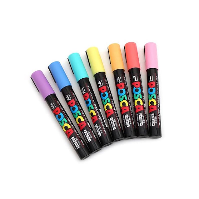 Puede incluir: Un conjunto de ocho marcadores de pintura Posca de color pastel. Los marcadores est&aacute;n dispuestos en semic&iacute;rculo con las puntas mirando al espectador. Los colores son lavanda, azul claro, turquesa, verde claro, amarillo, naranja, coral y rosa.
