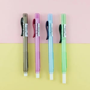 May include: Four Pentel Clic Eraser 2 mechanical pencil erasers in different colours: brown, pink, light blue, and green. Each eraser has a black plastic grip and a white eraser tip. The erasers are labelled "Pentel Clic Eraser 2" and "ZE11T-A", "ZEIIT-8", "ZE11T-C", and "ZE11T-D".