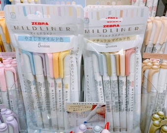 May include: Two packages of Zebra Mildliner highlighters. The package on the left has five pastel highlighters labeled "やさしさマイルド色" (soft mild color) and "5 colors". The package on the right has five highlighters in natural colors labeled "ナチュラルマイルド色" (natural mild color) and "5 colors".