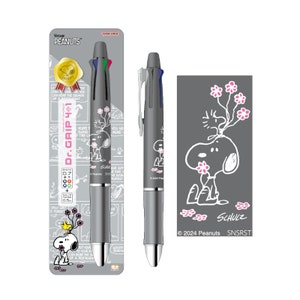 May include: A gray and silver multi-colored pen with a Peanuts character design. The pen has a black and white illustration of Snoopy with pink flowers on the barrel. The packaging features a Peanuts comic strip with Snoopy and the text "Vintage Peanuts" and "Dr. Grip 4+1".