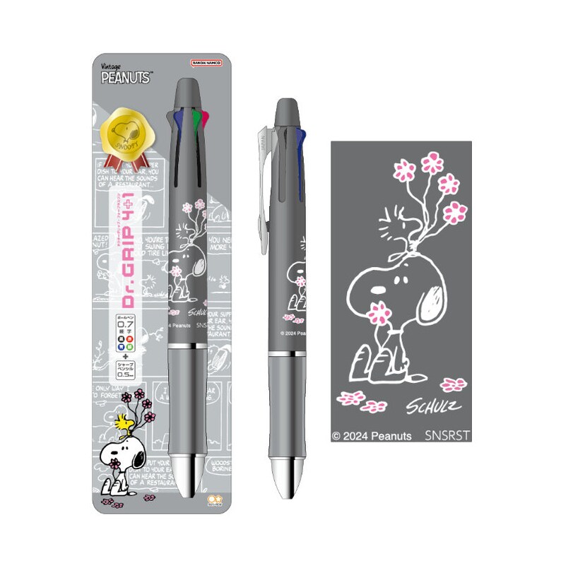 May include: A gray and silver multi-colored pen with a Peanuts character design. The pen has a black and white illustration of Snoopy with pink flowers on the barrel. The packaging features a Peanuts comic strip with Snoopy and the text "Vintage Peanuts" and "Dr. Grip 4+1".