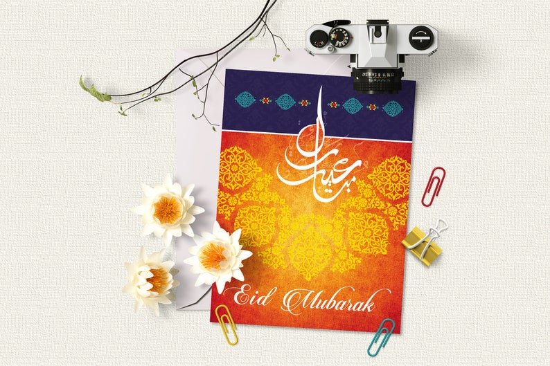 May include: A greeting card with an orange and yellow background featuring intricate gold designs and Arabic calligraphy. The card reads "Eid Mubarak" in white lettering.
