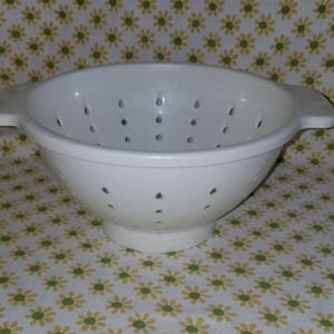 Peut inclure: Une passoire blanche avec de petits trous de drainage. L'ustensile de cuisine a deux poign&eacute;es et une forme de bol large et arrondie. La passoire est faite d'un mat&eacute;riau solide et opaque et est con&ccedil;ue pour &eacute;goutter les liquides des aliments.