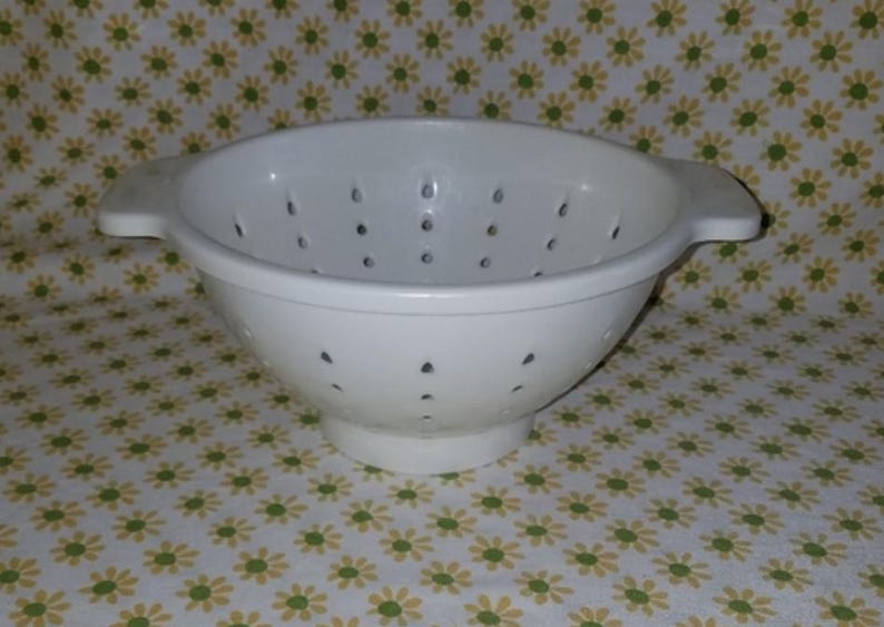 Peut inclure: Une passoire blanche avec de petits trous de drainage. L'ustensile de cuisine a deux poign&eacute;es et une forme de bol large et arrondie. La passoire est faite d'un mat&eacute;riau solide et opaque et est con&ccedil;ue pour &eacute;goutter les liquides des aliments.