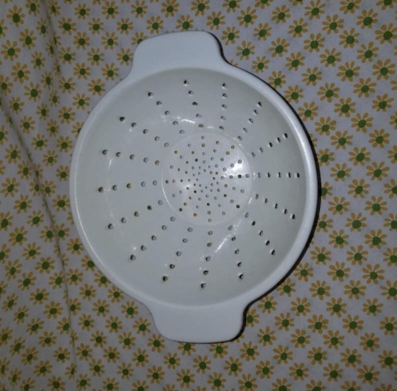 Peut inclure: Une passoire en plastique blanc avec deux poign&eacute;es. La passoire comporte de nombreux petits trous pour &eacute;goutter les liquides. La passoire est ronde et poss&egrave;de un bord l&eacute;g&egrave;rement &eacute;vas&eacute;. C'est un ustensile de cuisine.