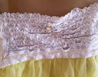 May include: A yellow sheer nightgown with white lace trim and a floral embellishment at the neckline.