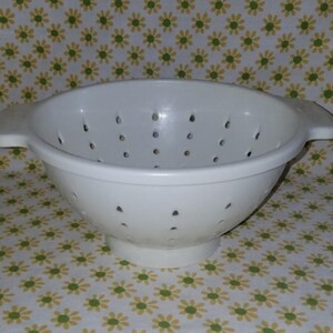 Peut inclure: Une passoire en plastique blanc avec une forme de bol large et de nombreux petits trous de drainage. Elle a deux poign&eacute;es et une base sur&eacute;lev&eacute;e. La passoire est con&ccedil;ue pour &eacute;goutter les liquides des aliments. Le fond est un motif floral.