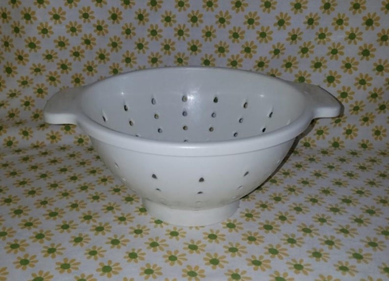 Peut inclure: Une passoire en plastique blanc avec une forme de bol large et de nombreux petits trous de drainage. Elle a deux poign&eacute;es et une base sur&eacute;lev&eacute;e. La passoire est con&ccedil;ue pour &eacute;goutter les liquides des aliments. Le fond est un motif floral.