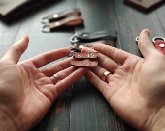 May include: Two small brown leather keychains with the initials "KJHS" embossed in white lettering.