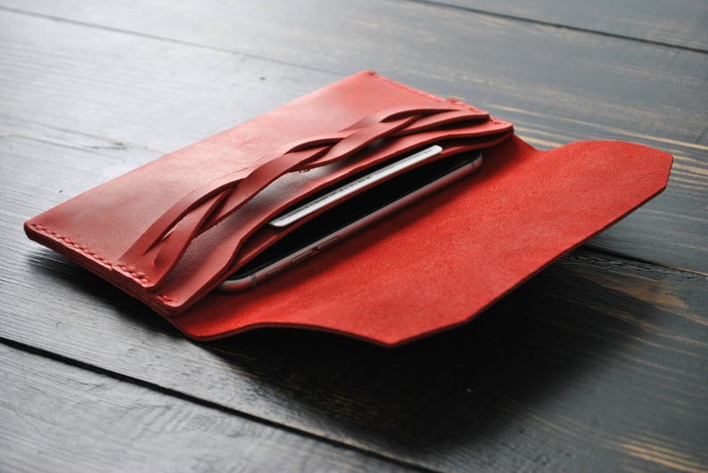 May include: Red leather wallet with a braided design and a phone and credit card inside.