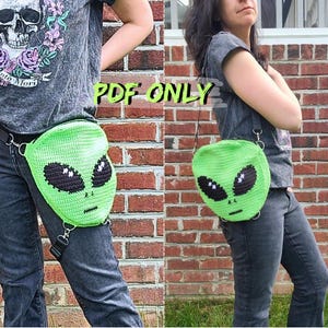 May include: A bright green crochet bag shaped like an alien head with large black oval eyes and a small stitched mouth. The bag features metal hardware for strap attachments and includes the text PDF ONLY printed in green over the image.
