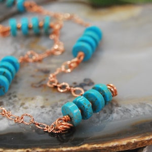 May include: A copper chain necklace with turquoise beads. The beads are stacked in groups of three and four, and the chain is delicate and intricate.