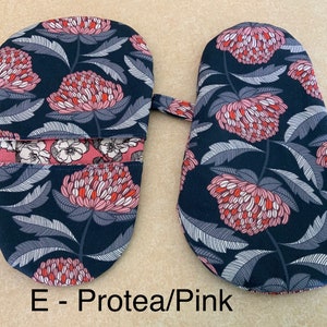 May include: A pair of oven mitts with a floral print. The mitts are dark blue with pink and red flowers. The text "E - Protea/Pink" is printed below the mitts.