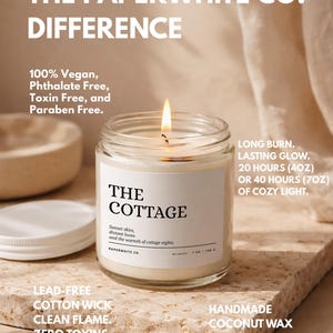 May include: A lit candle in a clear glass jar with a white label that reads "THE COTTAGE." The candle is on a stone surface. Text on the image includes "100% Vegan" and "Handmade Coconut Wax."