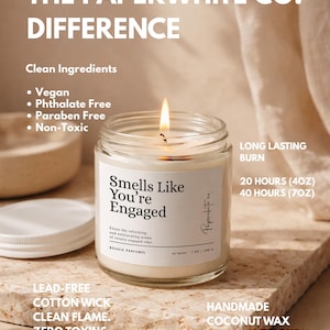 May include: A lit, clear glass jar candle with the text "Smells Like You're Engaged." The candle has a white label and a white lid. The candle is made with vegan, phthalate-free, paraben-free, and non-toxic ingredients. It has a lead-free cotton wick and a clean flame.
