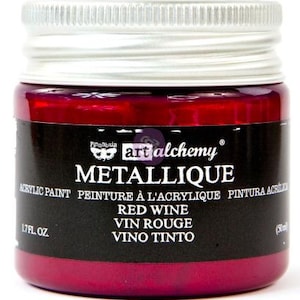 May include: A small glass jar of Finnabair Art Alchemy Metallique acrylic paint in the colour Red Wine. The jar features a silver screw-top lid and a black label with white text reading Metallique, Red Wine, 1.7 fl. oz. and 50 ml.