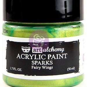 May include: A jar of bright green acrylic paint with a black lid. The label reads Art Alchemy Acrylic Paint Sparks Fairy Wings, 50 ml. The paint inside the clear jar is a vibrant, shimmering lime green colour with a metallic, reflective finish.