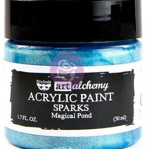 May include: A jar of Art Alchemy Sparks acrylic paint in the colour Magical Pond. The jar has a black lid and a white label with black text reading Art Alchemy Acrylic Paint Sparks Magical Pond 1.7 fl. oz. (50 ml) and a moth logo.