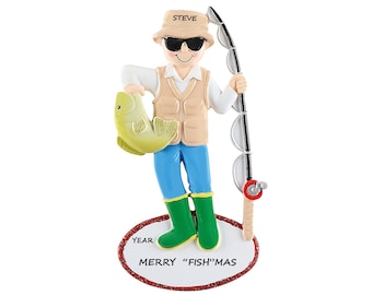 May include: A personalized Christmas ornament featuring a cartoon fisherman holding a fish and a fishing rod. The ornament is decorated with a red and white oval base that says "Merry "Fish"mas" and "Year".
