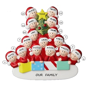 May include: A Christmas tree ornament shaped like a family of 14 people, each with a red hat and a smiling face. The ornament is decorated with a green Christmas tree, a yellow star, and the words "OUR FAMILY".