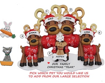 May include: Personalized Christmas ornament featuring a family of four reindeer wearing red sweaters with snowflakes. The reindeer are labeled "Dad", "Mom", "Emma", and "Liam". A small dog is included with the text "Aspen". The ornament includes the text "Our Family Christmas "Year"".