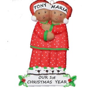 Puede incluir: Adorno navide&ntilde;o personalizado con una pareja en pijama rojo con lunares blancos, abraz&aacute;ndose. El adorno tiene los nombres "Tony" y "Maria" en los sombreros y el texto "Nuestro 1er a&ntilde;o de Navidad" en la base.