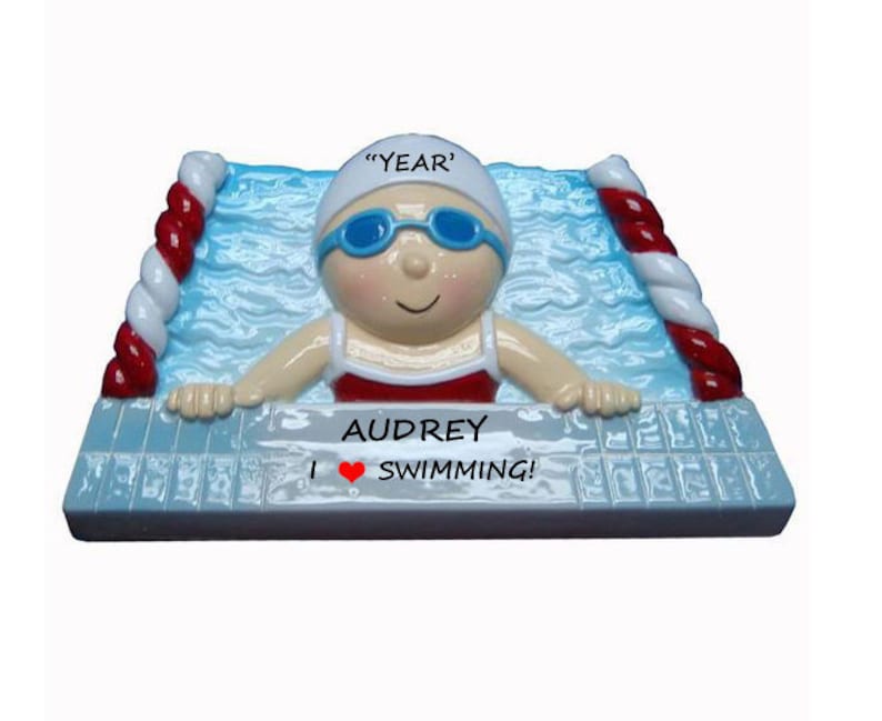 May include: A personalized Christmas ornament featuring a cartoon swimmer with a red swimsuit, blue goggles, and a white swim cap. The ornament is decorated with a blue pool and red and white lane lines. The text "Audrey I &hearts; SWIMMING!" is printed on the ornament.