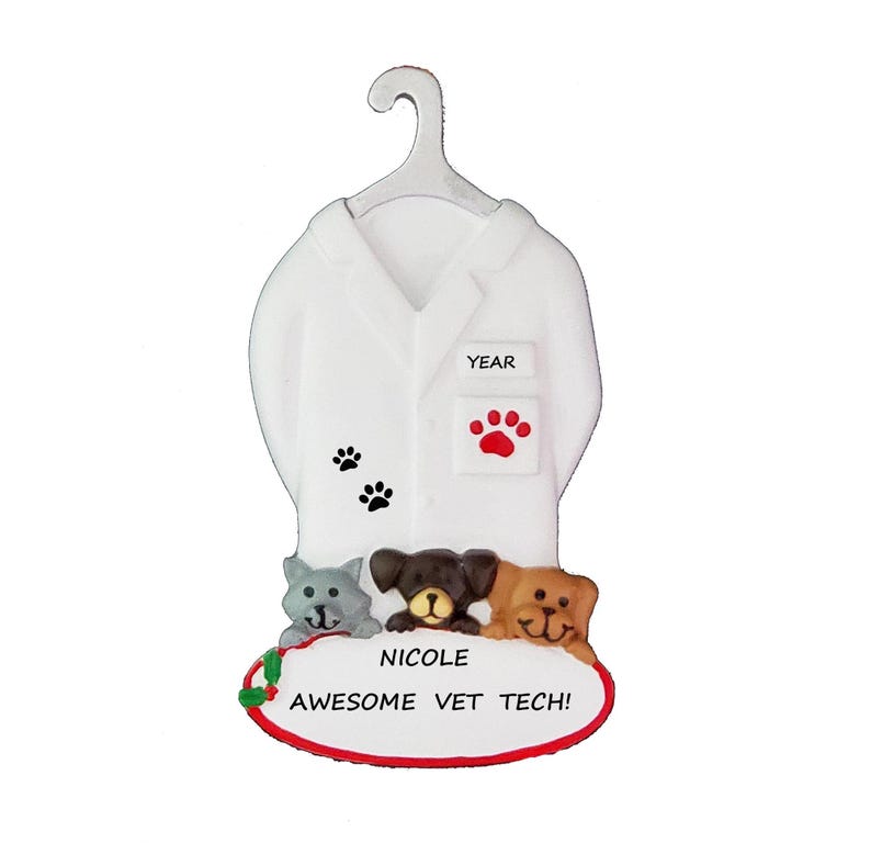 May include: White personalised ornament featuring a white lab coat with a red paw print and black paw prints, a grey cat, a brown dog, and a brown and white dog. The ornament has the text "Nicole Awesome Vet Tech!" and "Year" on it.