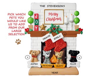 May include: Personalized Christmas ornament featuring a white brick fireplace with a mantle, stockings, and a "Merry Christmas" sign. The fireplace has a red and green garland with a gold star. There are two stockings with the names "Travis" and "Emily" on them. There are four pets below the fireplace: a dog named "Aspen", a cat named "Patches", a dog named "Rusty", and a dog named "Allie".