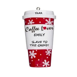 Op de afbeelding: Een koffiebeker ornament met een wit deksel en een rode body versierd met witte sneeuwvlokken. De beker heeft een witte band met de tekst "Coffee Lover" en "EMILY", en "SLAVE TO THE GRIND!". Bovenop zit een kleine metalen lus.