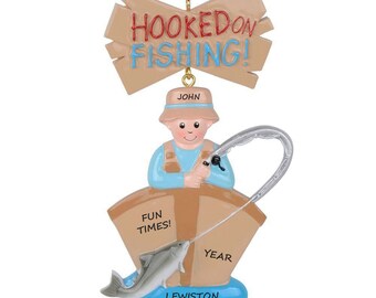 May include: A personalized Christmas ornament featuring a cartoon fisherman in a boat with a fish, a sign that says "Hooked on Fishing!" and the text "John, Fun Times!, Year, Lewiston Lake".