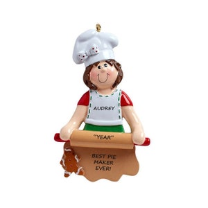 May include: A personalized Christmas ornament featuring a girl wearing a white chef's hat and a green apron. She is holding a rolling pin and a piece of dough with the text "Best Pie Maker Ever!" and "Year". The ornament is personalized with the name "Audrey".