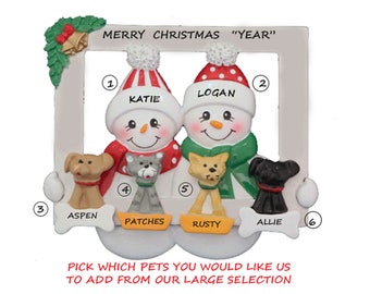 May include: Personalized Christmas ornament featuring a white frame with the text "Merry Christmas "Year"". Two snowpeople with red and green hats are holding pets. The snowpeople are labeled "Katie" and "Logan". The pets are labeled "Aspen", "Patches", "Rusty", and "Allie".