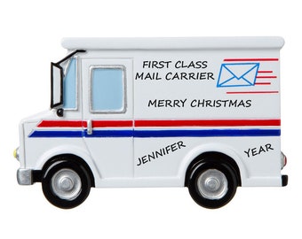 May include: White mail truck Christmas ornament with red and blue stripes. The ornament has the text "First Class Mail Carrier" and "Merry Christmas".