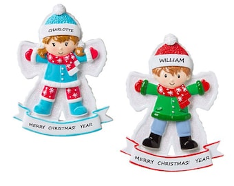 May include: Two personalized Christmas ornaments shaped like snow angels. The girl angel is wearing a blue hat, blue jacket, red pants, and white boots. The boy angel is wearing a red hat, green jacket, blue pants, and black boots. Both ornaments have a white banner with the text "Merry Christmas! Year".