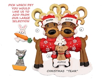 May include: Personalized Christmas ornament featuring a couple of reindeer wearing red sweaters with snowflakes, holding a small dog. The reindeer are labeled "Mark" and "Katie" and the dog is labeled "Aspen". The ornament also includes a choice of three additional pet ornaments: a rabbit, a cat, and a dog.