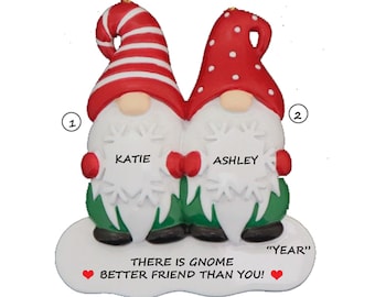 May include: Personalized Christmas ornament featuring two gnomes with red and white hats, holding hands. The gnomes have the names "Katie" and "Ashley" written on their snow-covered bellies. The ornament reads "There is gnome better friend than you!" and "YEAR".
