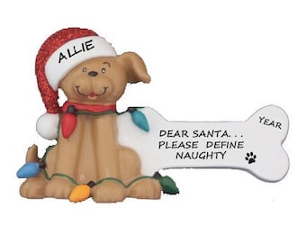 May include: A Christmas ornament featuring a brown dog wearing a red Santa hat with the name "Allie" on it. The dog is holding a white bone with the text "Dear Santa... Please Define Naughty" and a paw print. The bone also has the word "Year" on it.