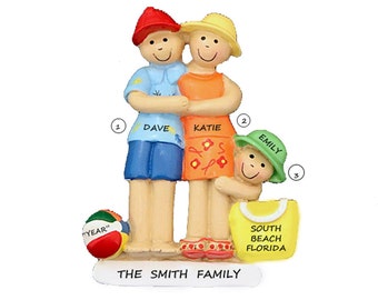 May include: A Christmas ornament featuring a family of three, a man, a woman, and a child, wearing summer clothes and hats. The ornament is decorated with the text "The Smith Family", "South Beach Florida", and "YEAR".