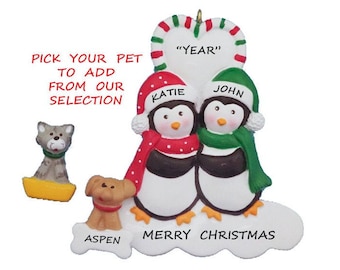 May include: Personalized Christmas ornament featuring a penguin couple with the names Katie and John, a heart with the text "YEAR", and the words "Merry Christmas" and "Aspen".