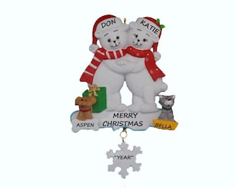 May include: A Christmas ornament featuring two white polar bears wearing Santa hats and red scarves, hugging. The ornament includes the names "Don" and "Katie", the words "Merry Christmas", and a snowflake that says "Year".
