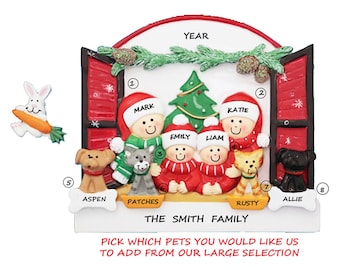 May include: A personalized Christmas ornament featuring a family of five with pets. The ornament includes the names Mark, Emily, Liam, and Katie. The text "THE SMITH FAMILY" is displayed. The ornament also includes a bunny with a carrot.