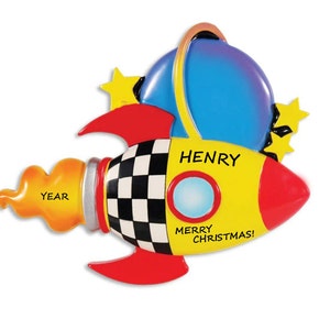 May include: A yellow and red rocket ship Christmas ornament with a black and white checkered pattern. The rocket has a blue planet with a ring around it and a flame coming out of the back. The ornament says "HENRY" and "MERRY CHRISTMAS!"