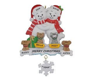 May include: A white polar bear couple Christmas ornament with red and white striped scarves, holding a green gift box. The ornament also features two cats and two dogs with their names: Bella, Missy, Buddy, and Aspen. The text "Merry Christmas" is written on the base of the ornament. A snowflake charm with the text "YEAR" hangs from the ornament.