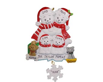 May include: White polar bear family Christmas ornament with red and white scarves and hats. The ornament includes two parents, two children, and two dogs named Aspen and Patches. The text on the ornament reads "The Taylor Family".