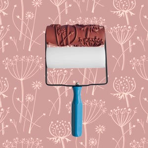 Pode incluir: Um rolo de pintura com um padrão de design floral. O rolo é azul e tem uma cabeça de rolo de espuma branca. O padrão é de flores brancas delicadas sobre um fundo rosa.